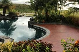 Red stained deck curving around a lagoon style pool