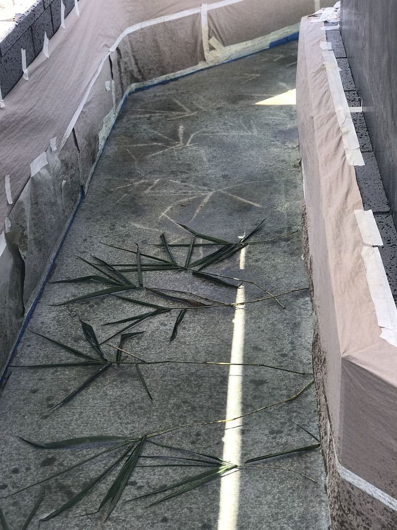Real fronds laid across the memorial slab to print their shapes into the stain