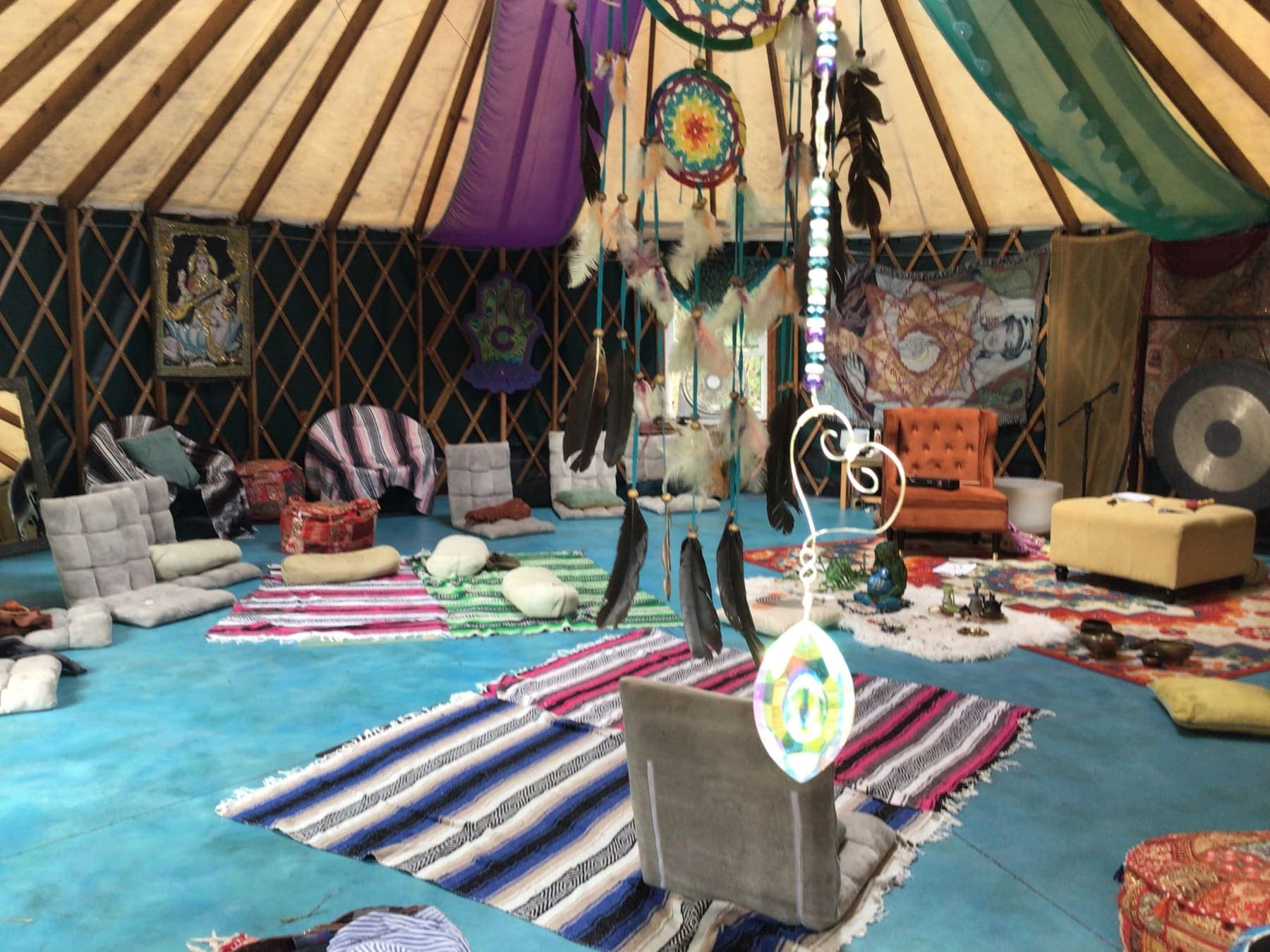Rugs and cushions laid out on the yurt's ocean blue floor